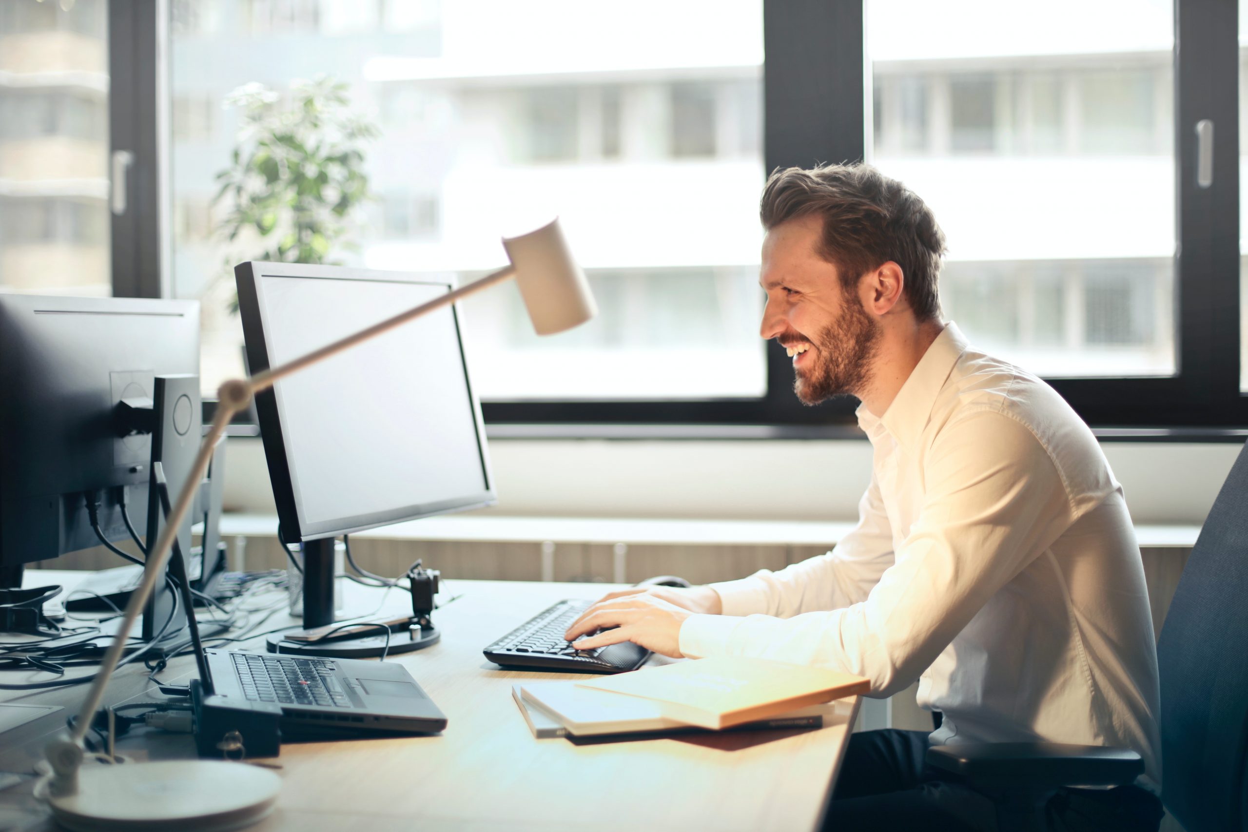 Lachende man achter een computer aan het werken